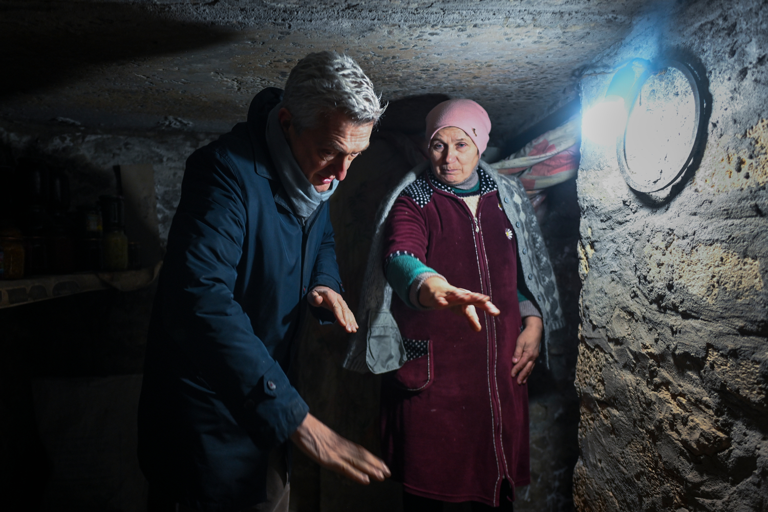 UNHCR's Filippo Grandi stands in a bunker with a woman from Ukraine.