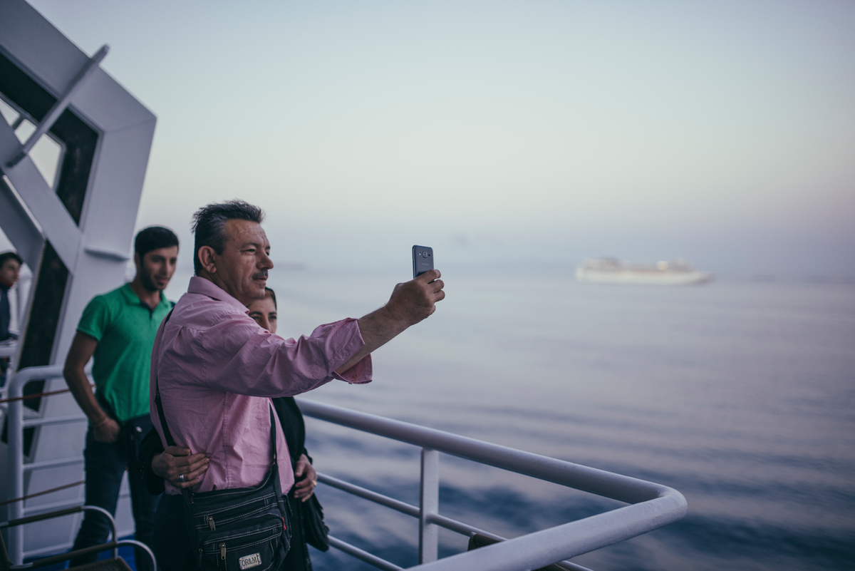 Greece, father, mother and young son taking a a selfie aboard a ship.
