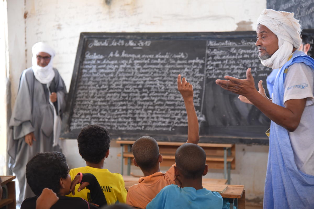 Mauritania. Malian refugee teacher encourages his class of children