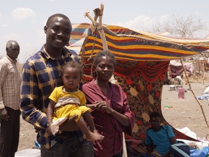 A man stands next to a woman holding a little girl in a yellow dress.