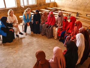 Refugee schoolgirls and staff from international organizations sit in a classroom. 