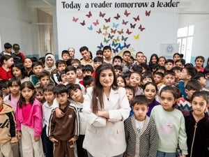 A woman stands in the middle of a classroom full of young students
