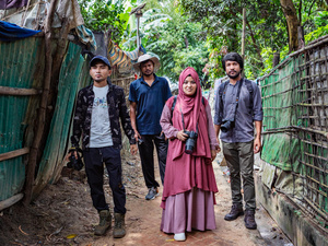 Four photographers pose for a photo in the jungle, between two fences