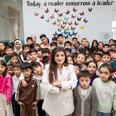 A woman stands in the middle of a classroom full of young students
