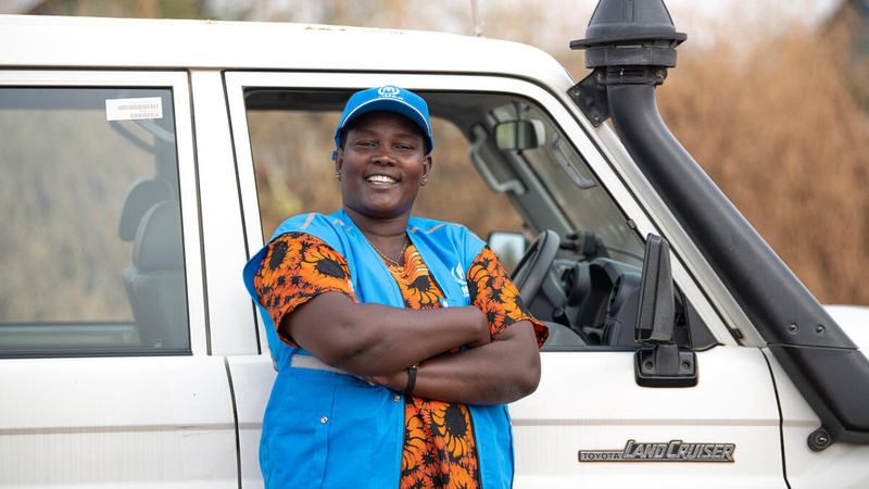  Rose, a UNHCR driver, smiles for the camera as she stands in front of the Landcruiser she drives.