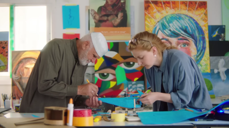 A Syrian man and a UNHCR staff member work together to build a toy