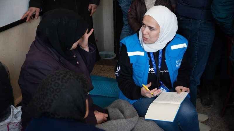 A UNHCR staff member takes notes as she speaks with a woman inside a shelter in Aleppo, Syria.