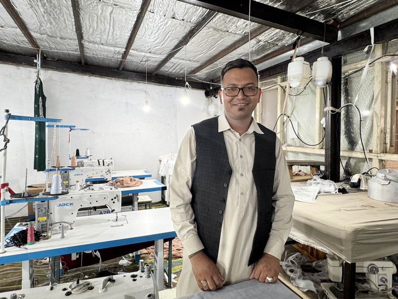 Ali Allah stands inside his tailoring workshop.