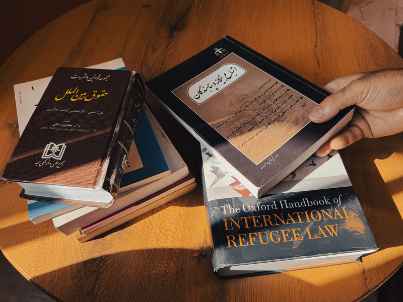 A stack of books on refugee law in Persian and English.