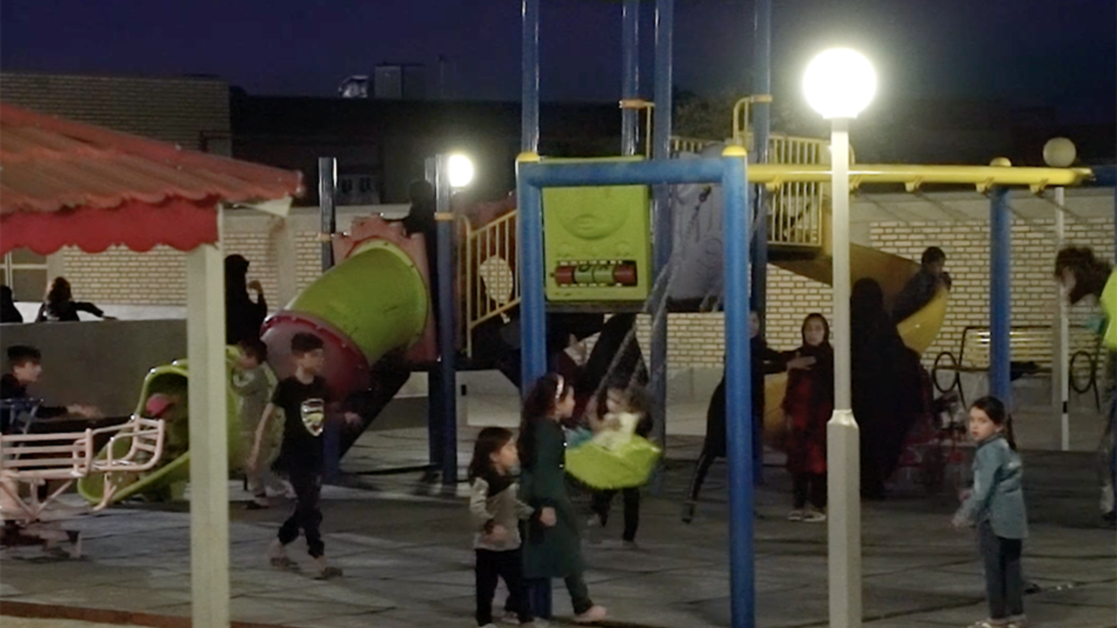 Children playing at a lit-up playground at night in Iran. UNHCR provided solar lights so communities are able to do activities after the sun sets.
