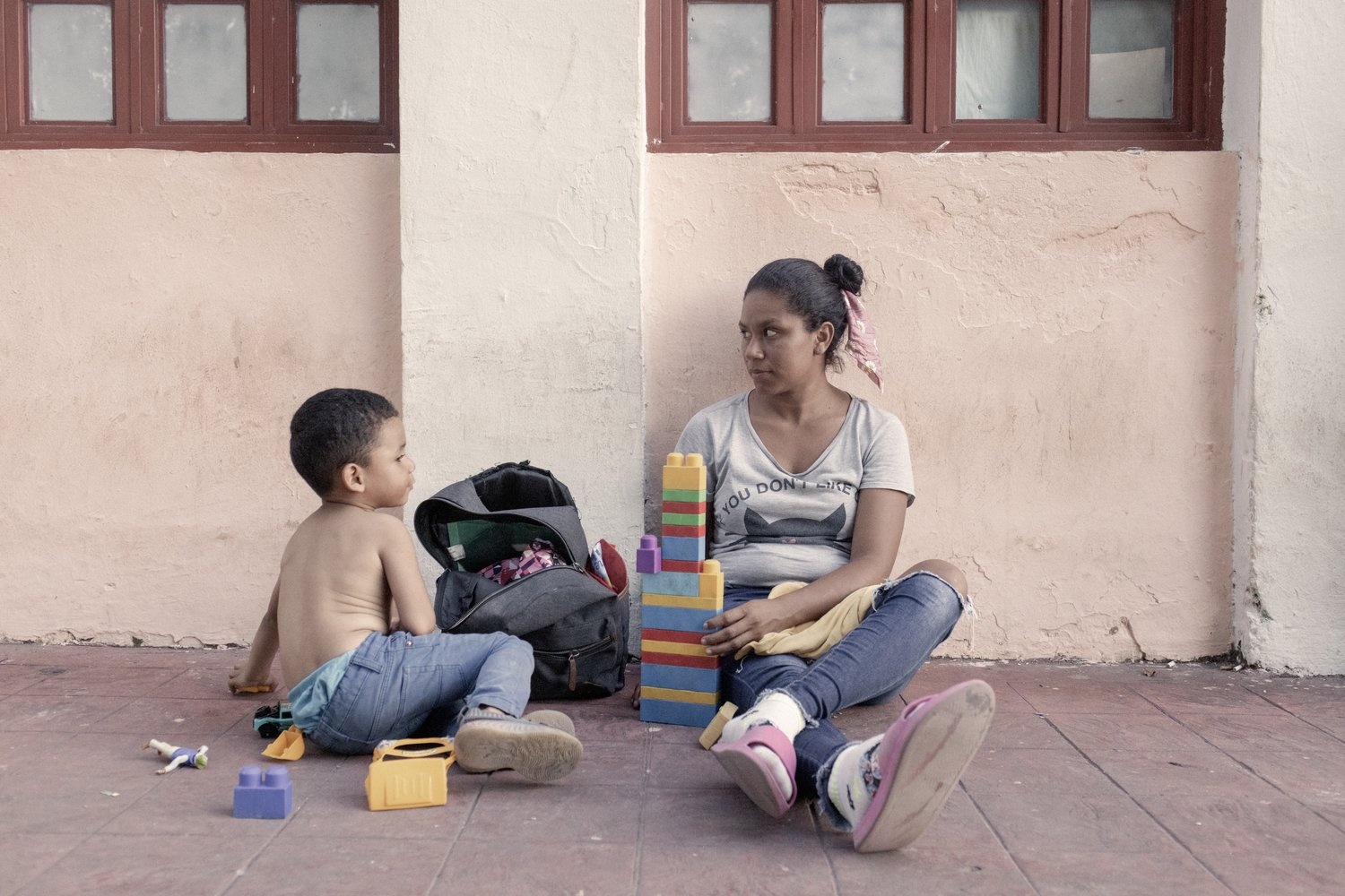 A woman and a young boy sit on the ground playing with lego.