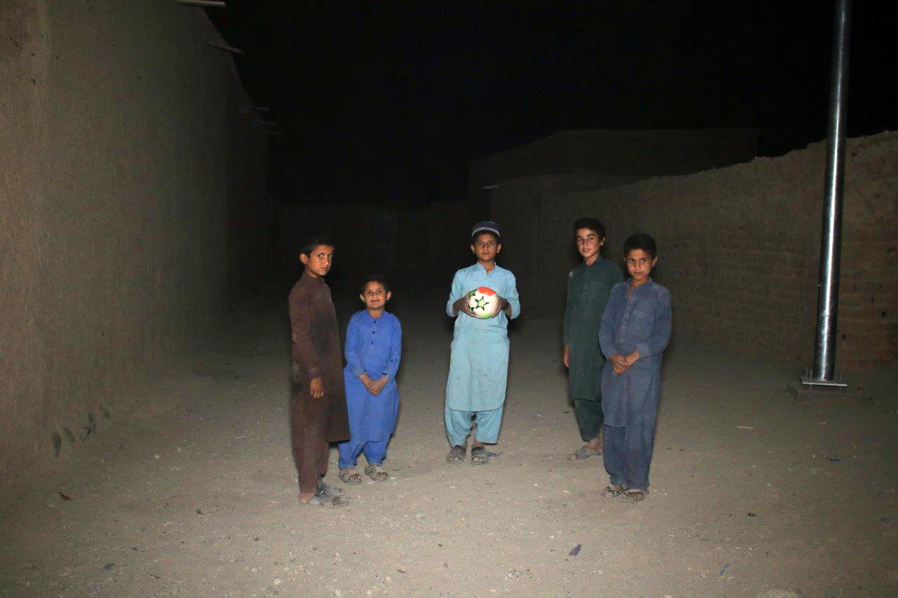 Children, including Mohmmad Waris, in Chaghi Refugee Village gather to play football during nighttime. 