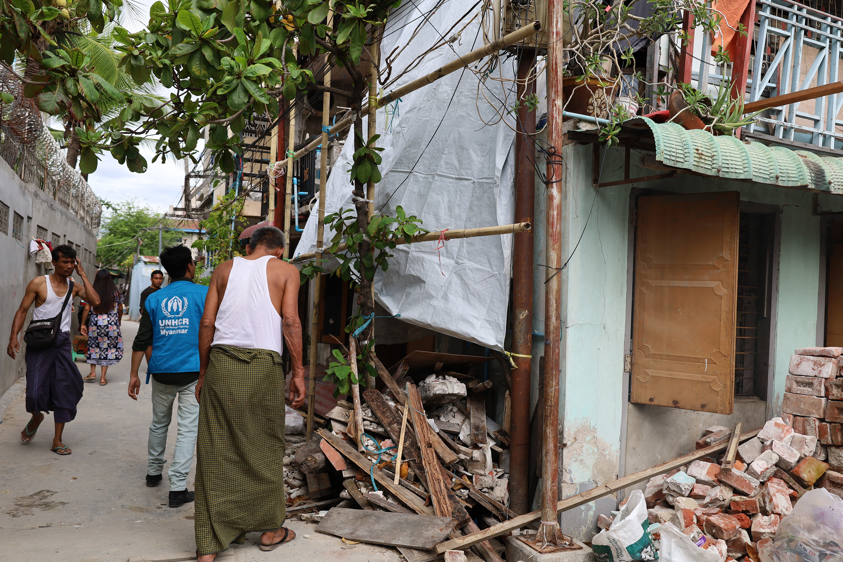  Ko Thein Naing stands outside a neighbor’s damaged house, taking part in the community effort to rebuild after the earthquake