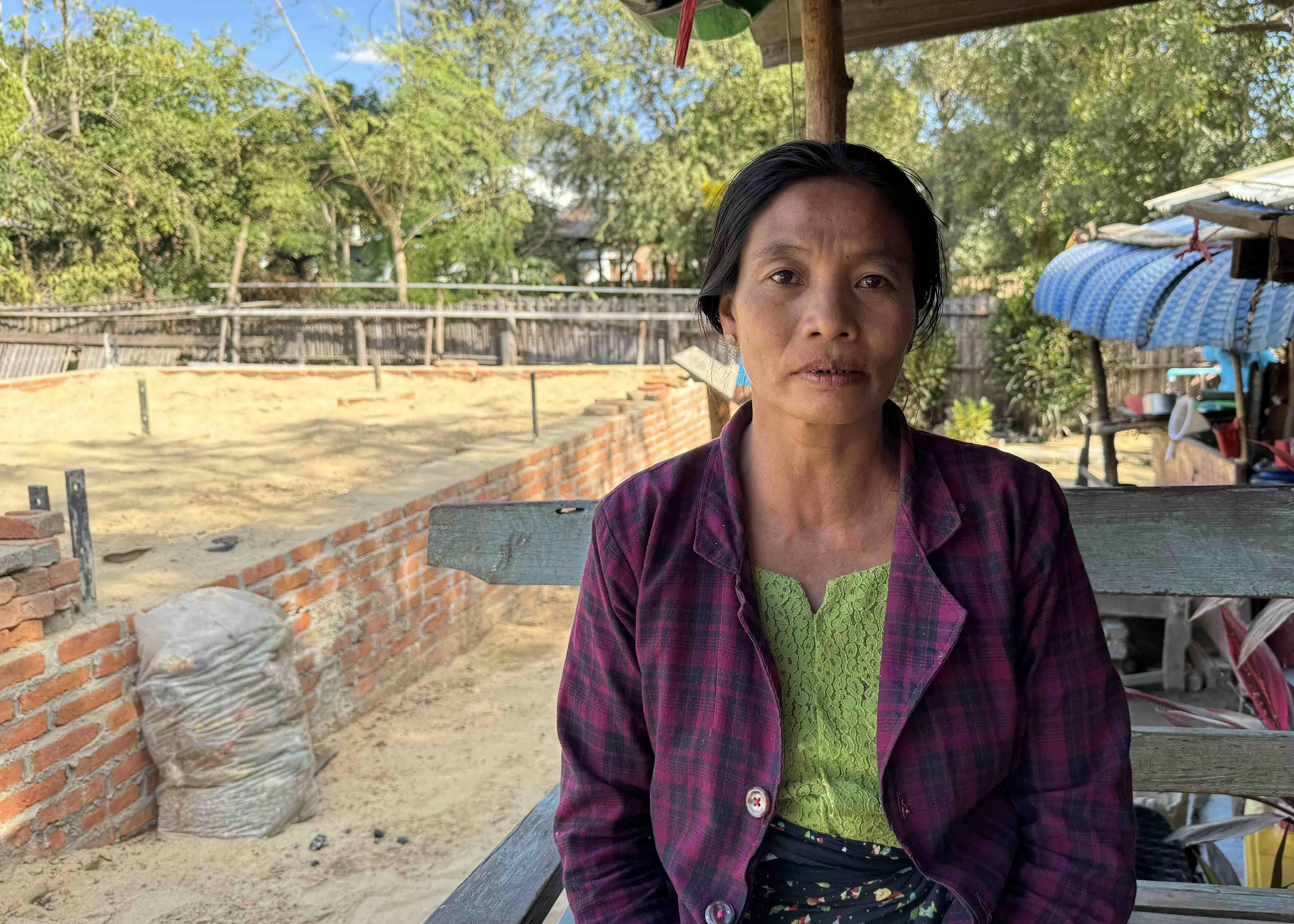 Ma Tin Tin Mya sitting in front of the new foundation of her home.