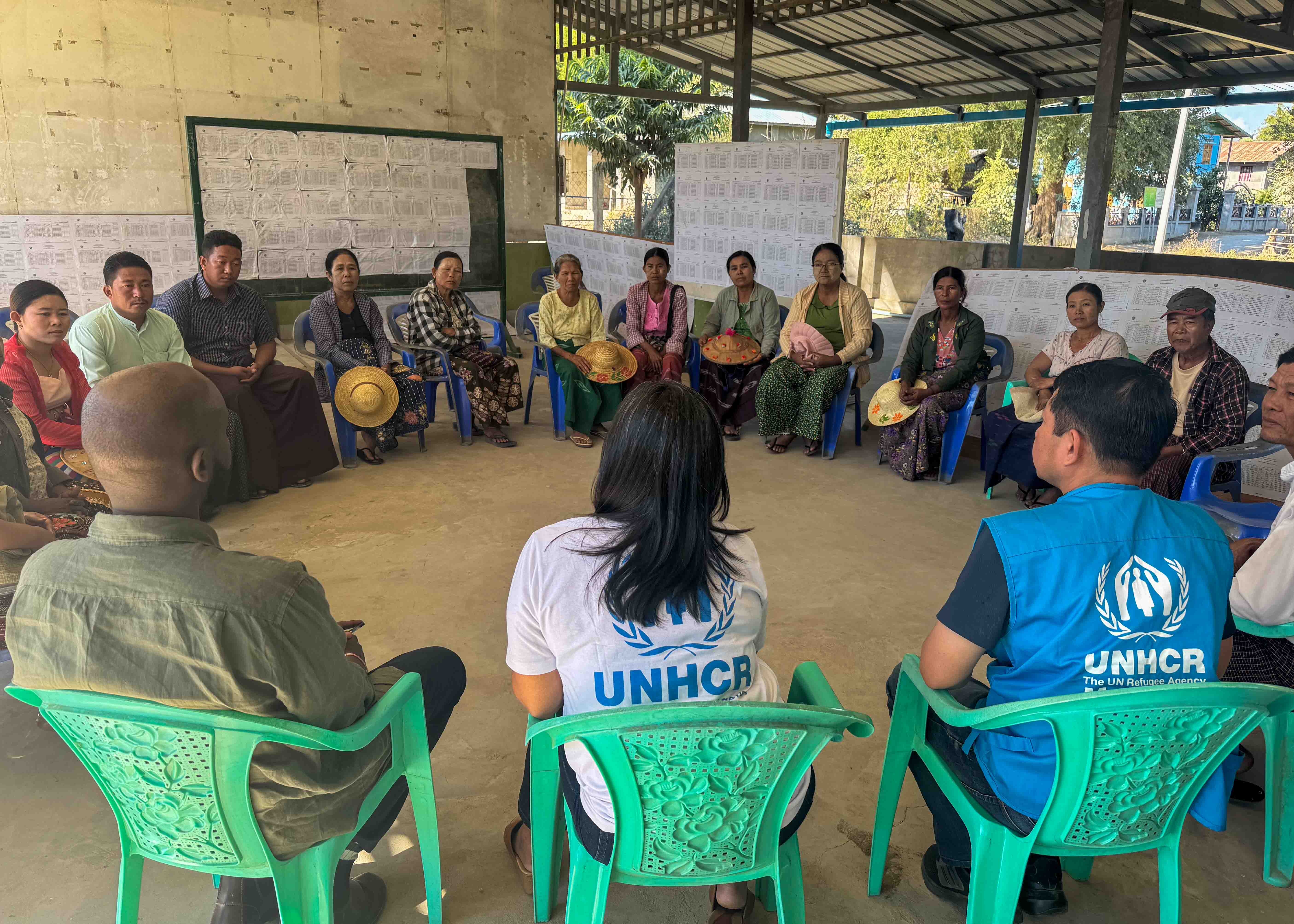UNHCR staff sit and discuss with village committee members.