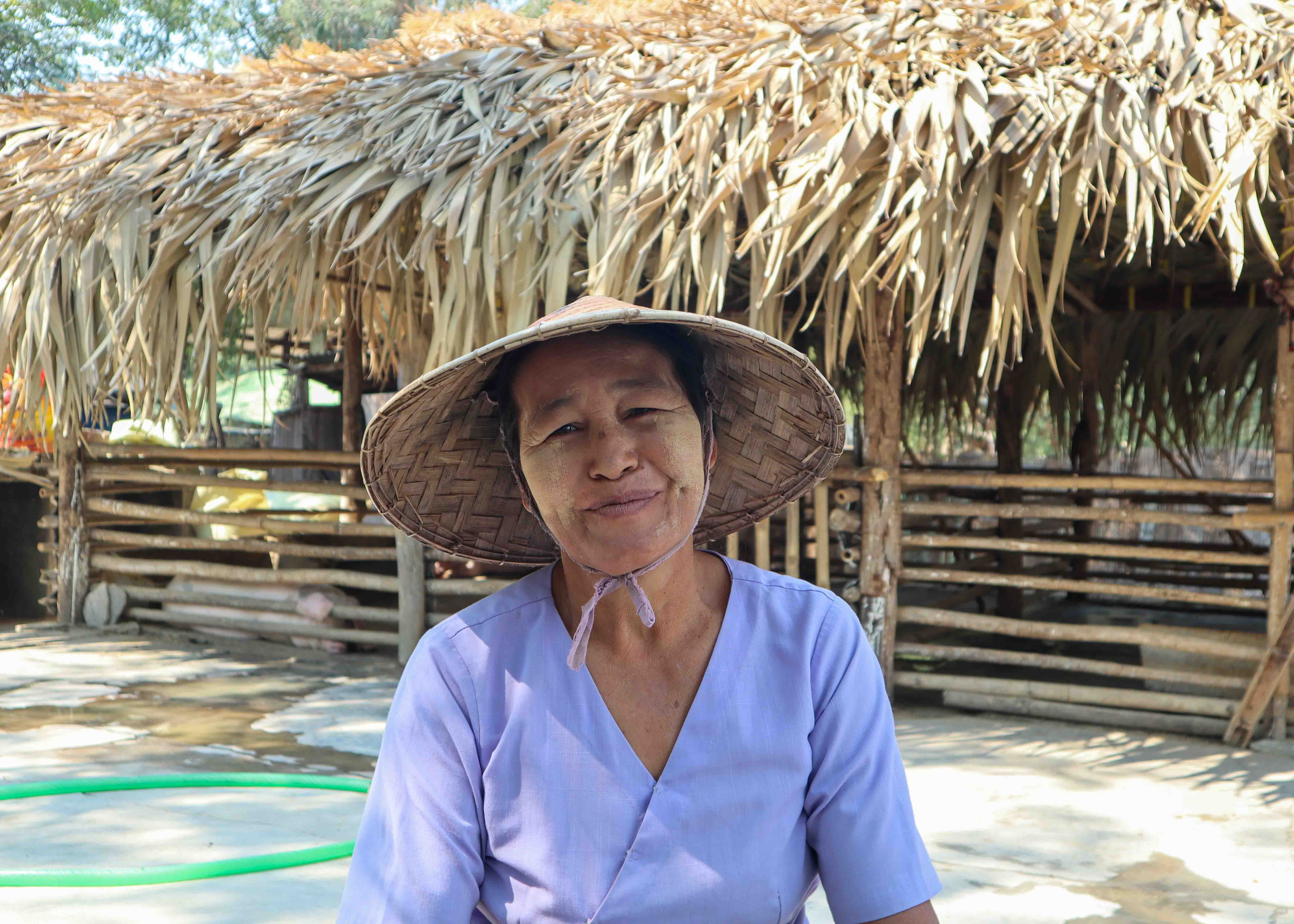Daw San Myint sitting in front of the community pig shed which UNHCR and partners helped build. 
