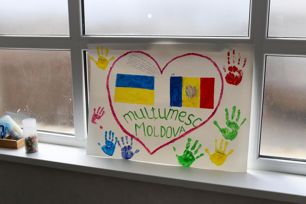 A child's painting showing the flags of Ukraine and Moldova surrounded by a heart and handprints is fixed to a window
