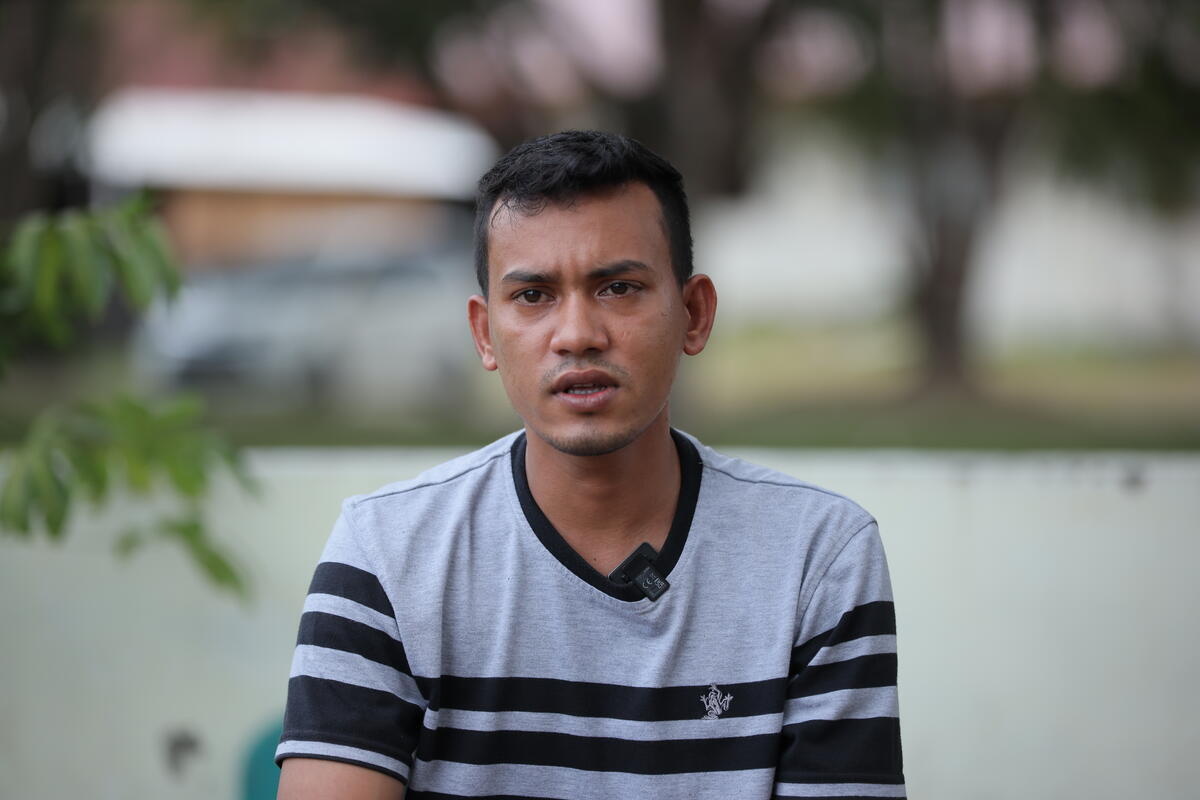 A man sits outside a temporary refugee shelter.