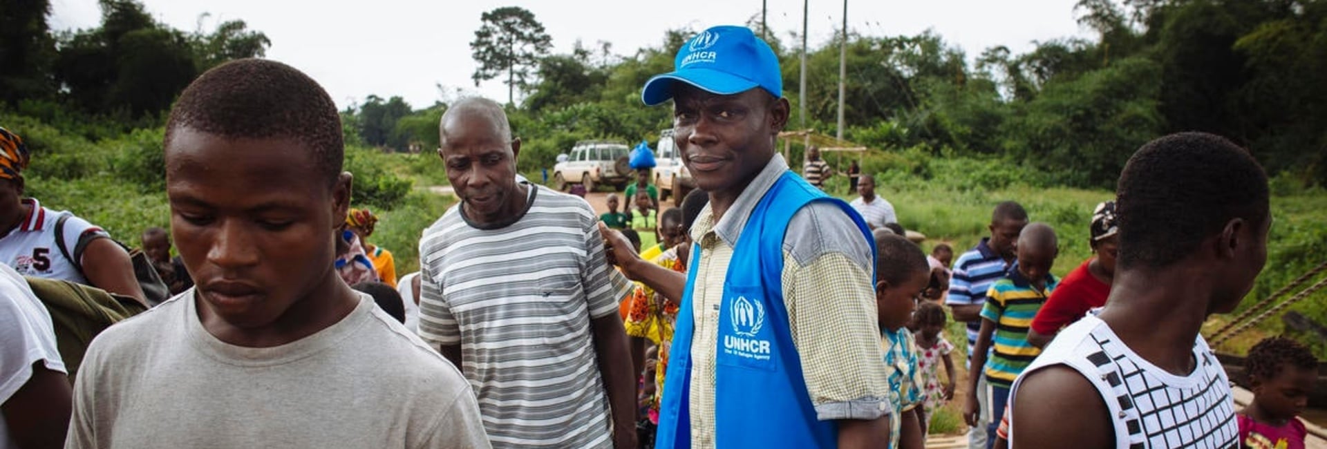 A UNHCR staff member helps refugees board a ferry that will take them home to Côte d'Ivoire.