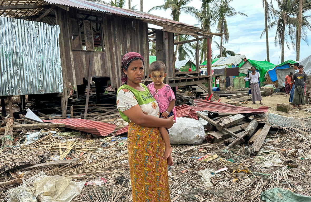 A woman holds her small child surrounded by the debris leftover from a severe storm.