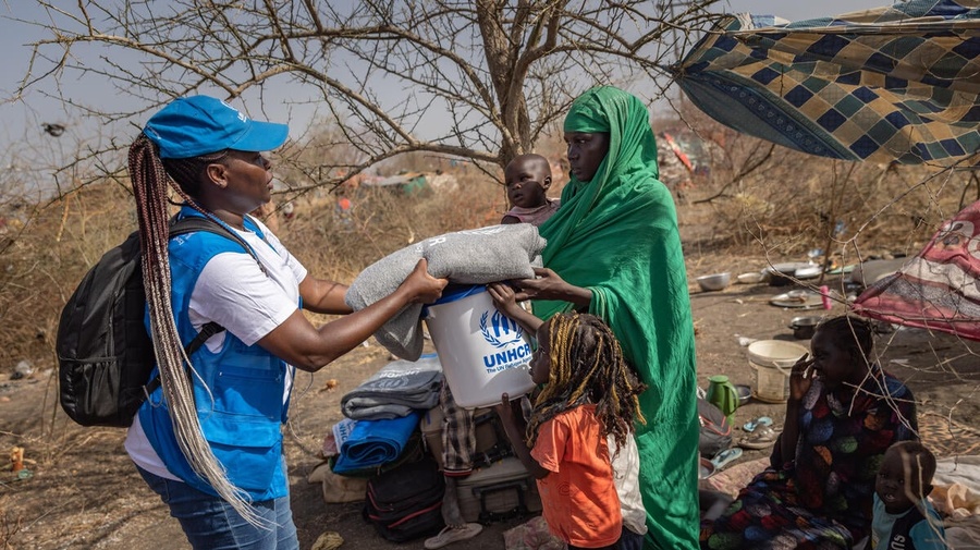 A South Sudanese returnee receives a blanket and bucket from a UNHCR staff member.