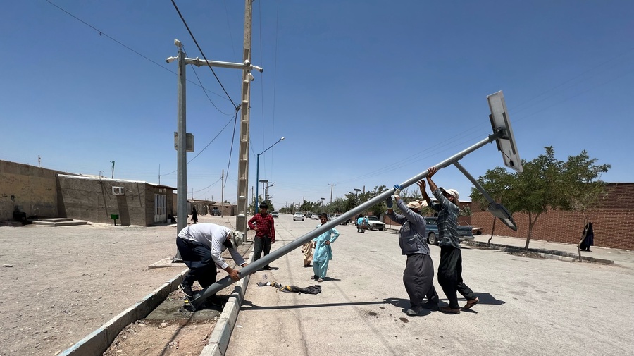 Workers put up a solar street light in Bardsir settlement, Iran.