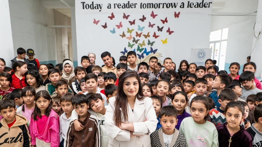 A woman stands in the middle of a classroom full of young students