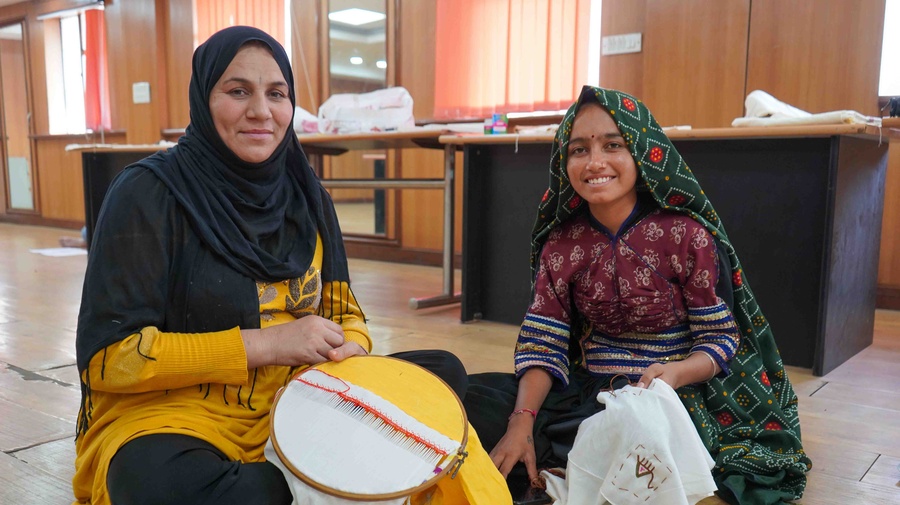 Artists Farida and Rasilaben weave together during the workshop, exchanging stitches shaped by generations.