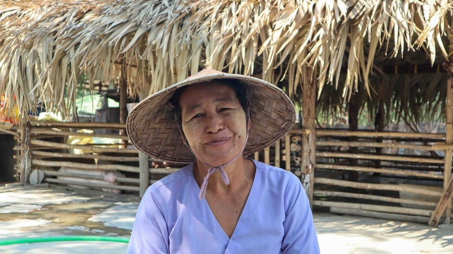 Daw San Myint sitting in front of the community pig shed which UNHCR and partners helped build. 
