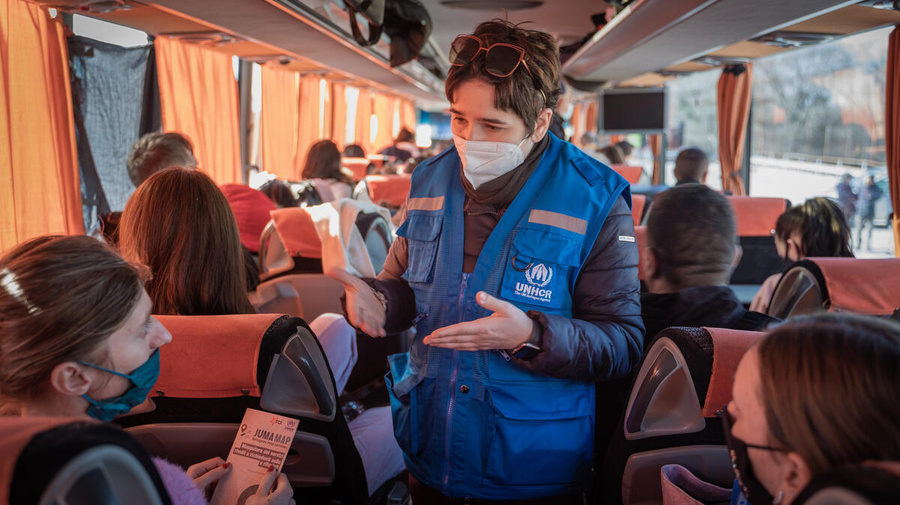 A UNHCR staff member discusses with Ukrainian refugees in a bus.