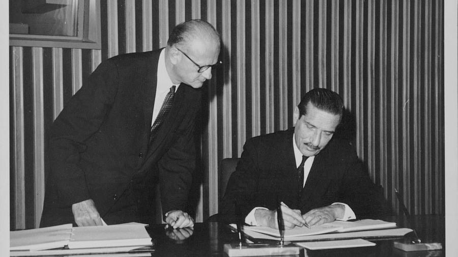 Black and white photograph of a man signing the final act of the Convention on the Reduction of Statelessness.