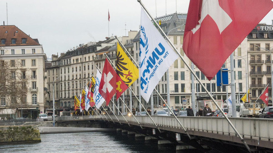UNHCR’s flag flies alongside the Swiss flag on a bridge over a river. 