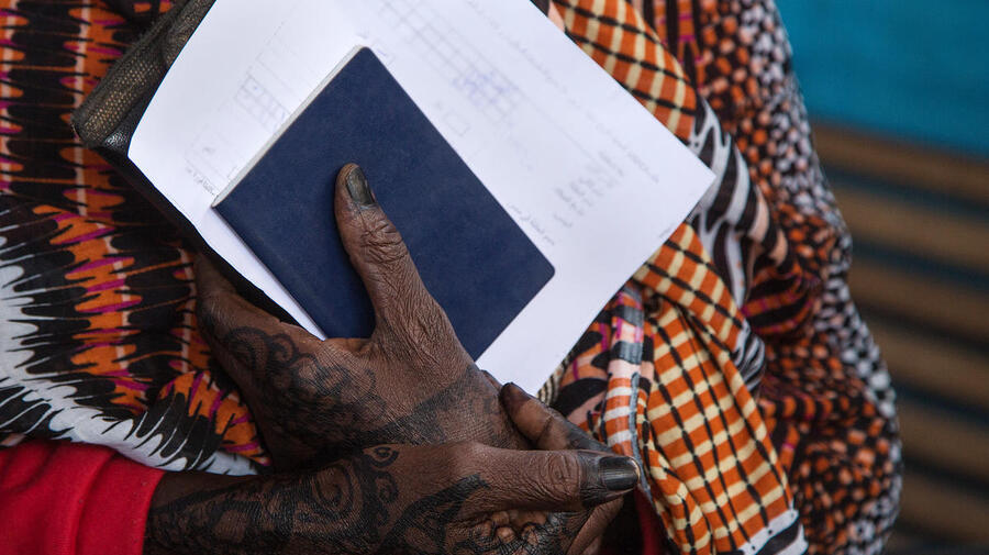 Folded hands hold blue and white document papers.