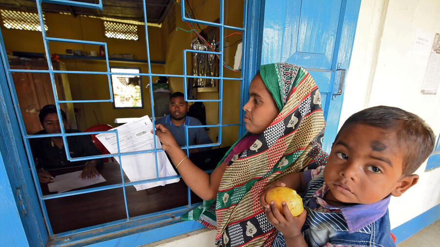 A mother carrying her son arrives to check her name on the draft list of the National Register of Citizens at an NRC centre in Chandamari village, India, 