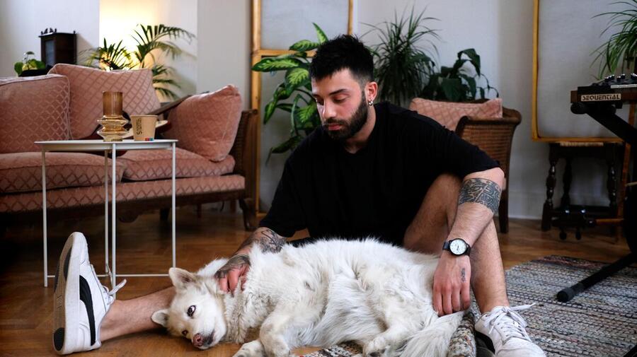 Belgium. Syrian refugee and musician Bassel cuddles his white shepherd dog Stella in their new home