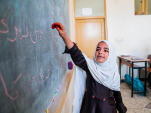 Ein kleines Mädchen in einer Grundschule in Afghanistan schreibt im Unterricht an der Tafel. 