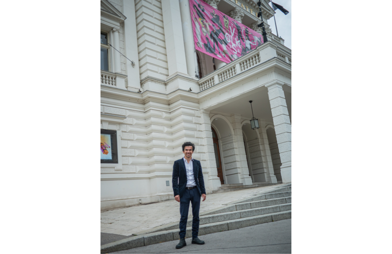 Mann vor dem Wiener Volkstheater blickt l&auml;chelnd in die Kamera