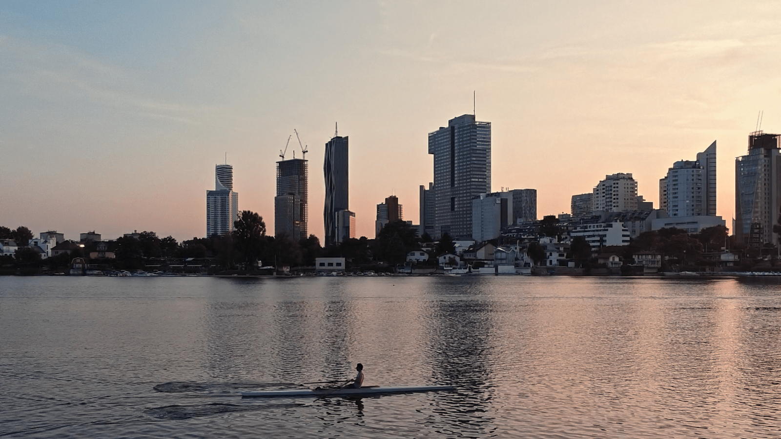 Ein Ruderboot auf der Donau vor Hochhäusern in Wien