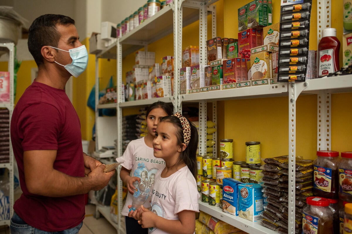 A man and his two daughters browse food items in a small grocery store.