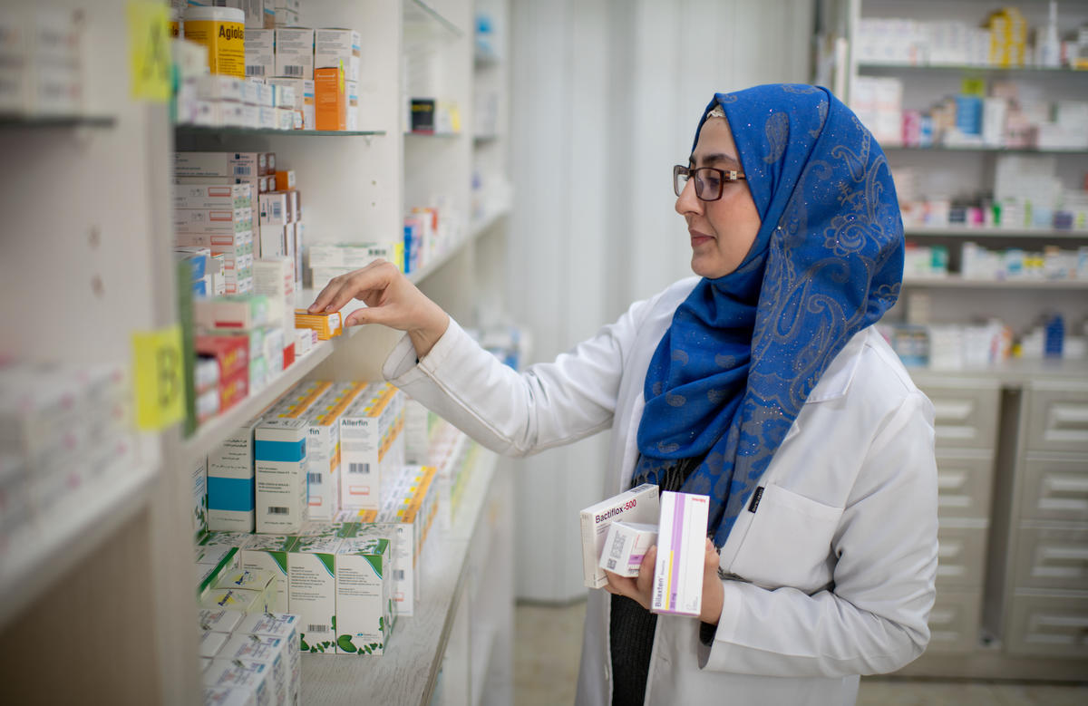 A woman restocks medicines in a pharmacy
