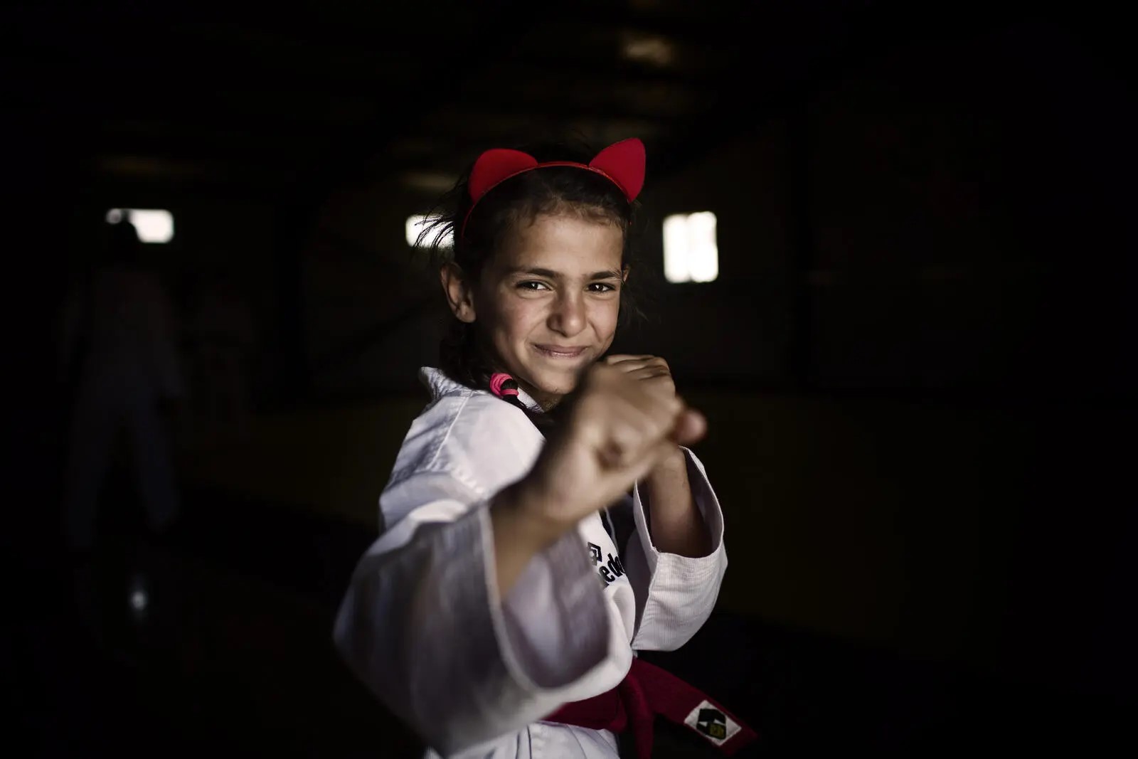A young girl in martial arts robes poses in a defensive stance