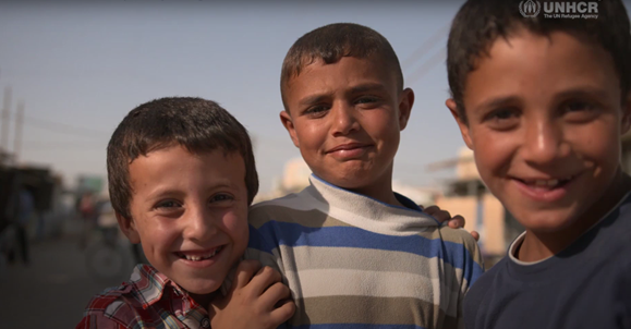Three young boys smile at the camera