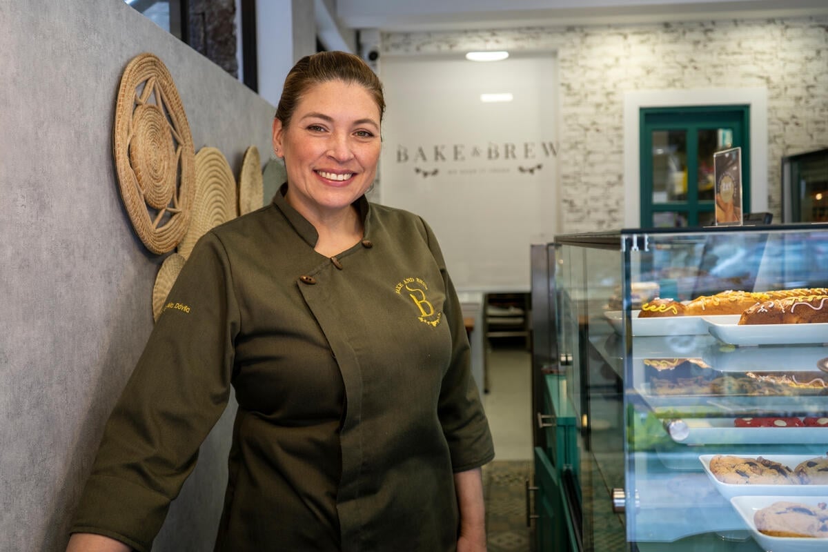 A Venezuelan woman stands smiling in a pastry shop