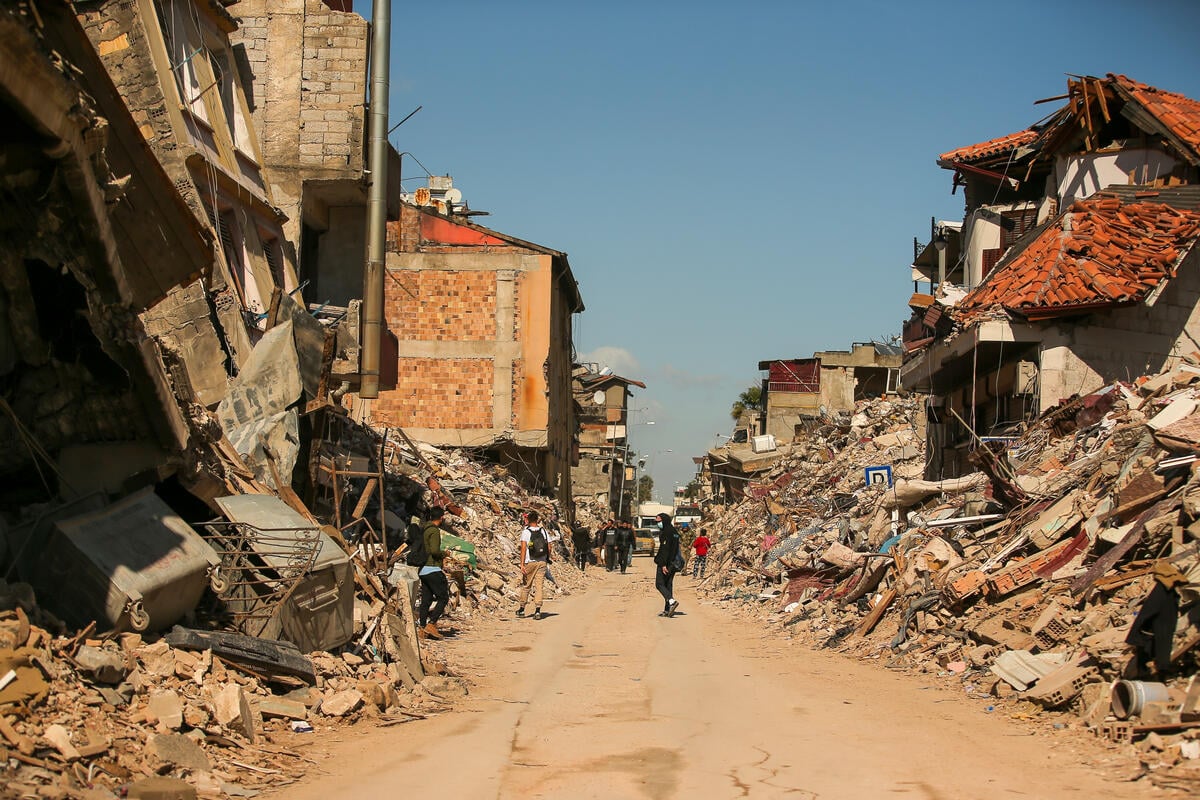 Residents walk past the rubble of destroyed buildings shortly after the earthquakes in Hatay, Türkiye.