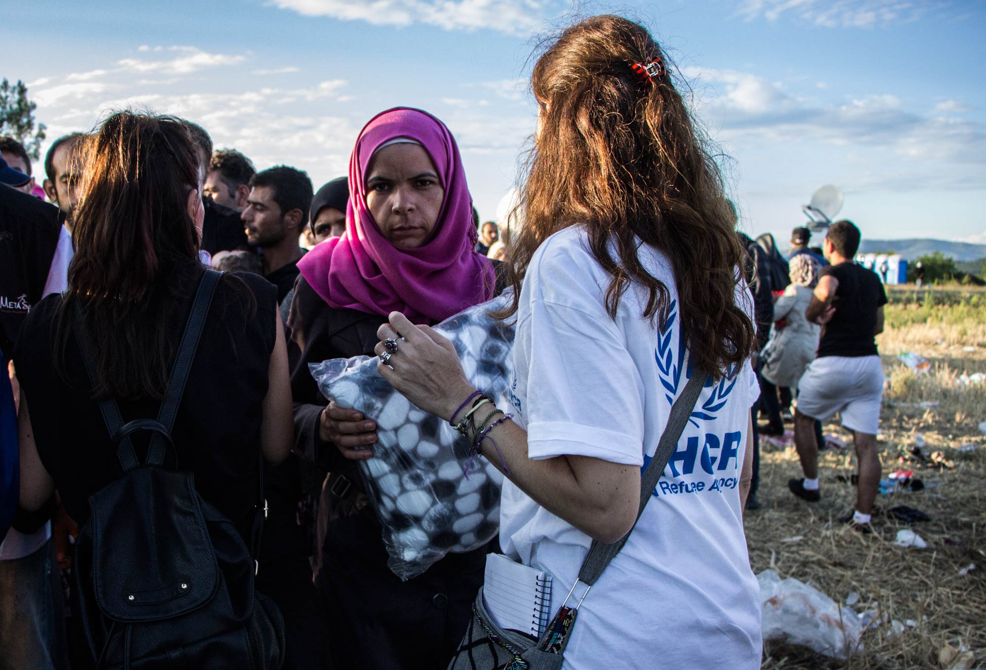 A UNHCR staff member distributes blankets to people waiting to cross the Greek-FYR Macedonian border.