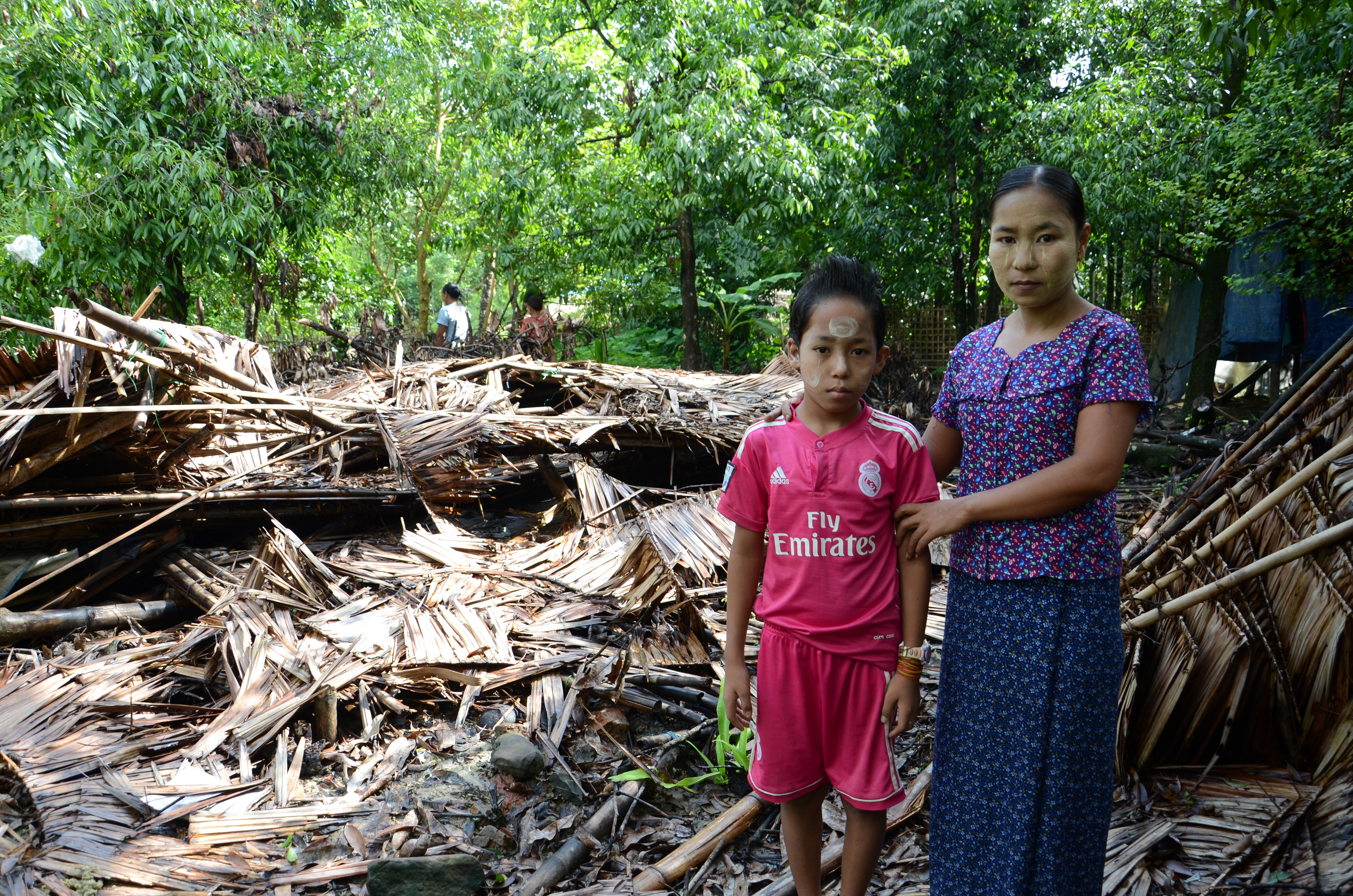 Ma Nge and her 10-year-old son stand outside the remains of their home in a small village in Ponnagyun township, Rakhine State.