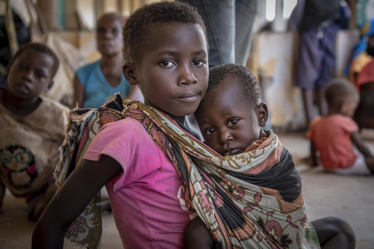 Mozambique. Rosa, age 7, holds her younger brother, Manuel, in a shelter for women and children in Buzi