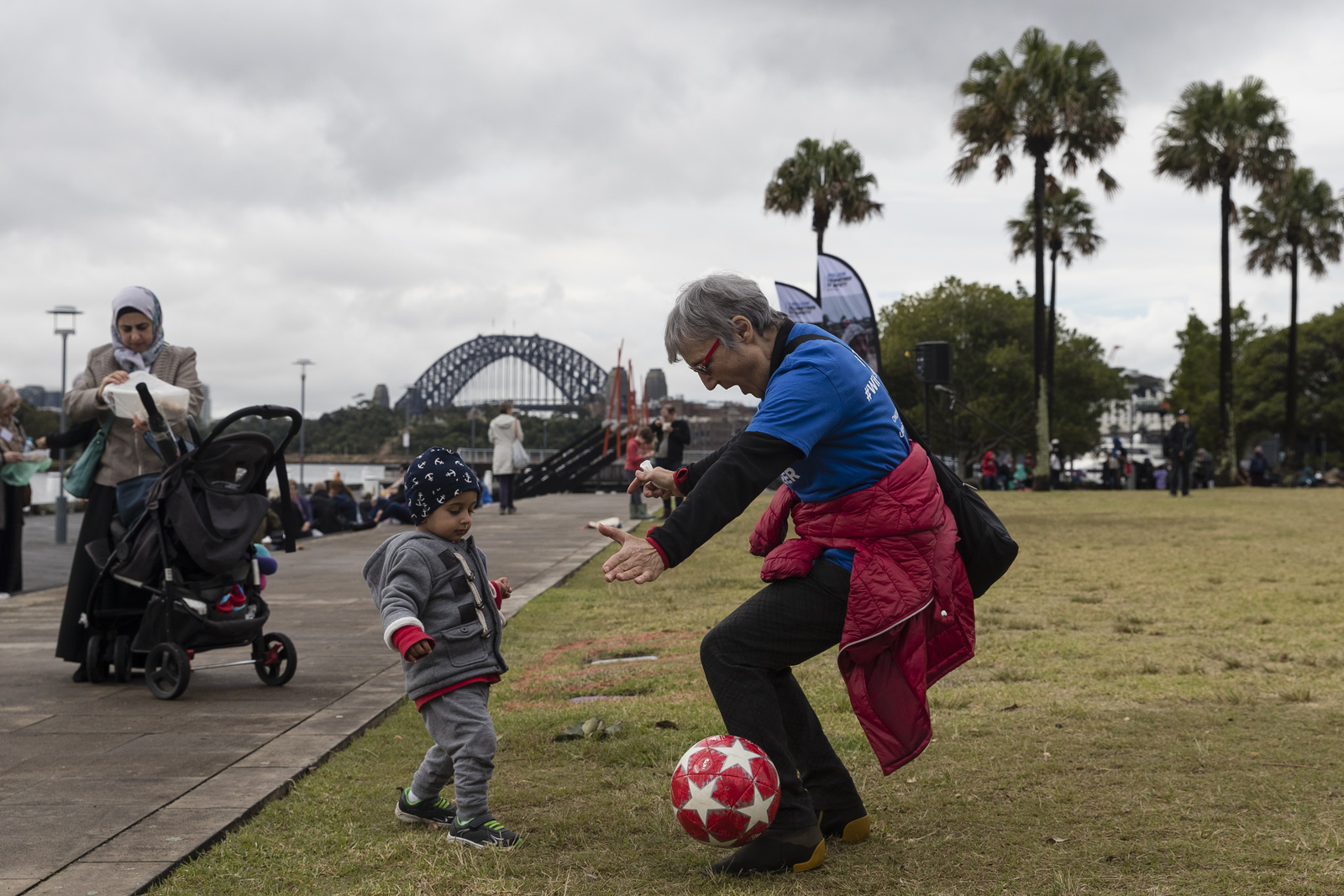 Spontaneous games of football breakout as Australians walk together with their neighbours from refugee backgrounds around Sydney harbour to celebrate World Refugee Day.