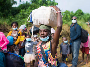 A refugee returning home to Côte d'Ivoire holds a bag on his head as he walks with other refugees.