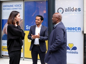 Three members, from Refugee Committees and UNHCR standing and having a conversation in a community centre for refugees in Brussels